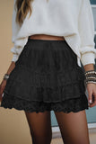 Person wearing a black lace skirt and white sweater with bracelets on.
