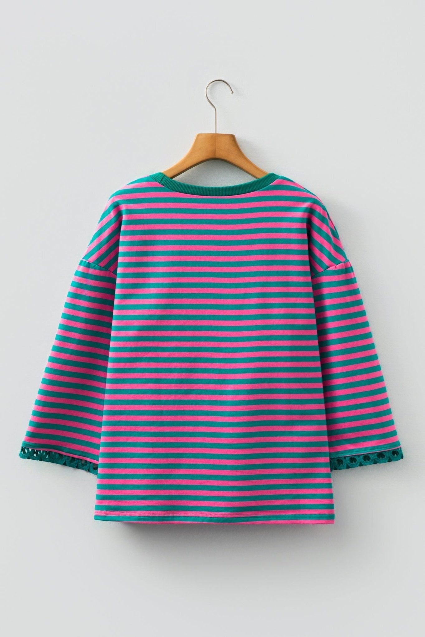 Striped dress with pink and green horizontal stripes on a hanger against a white background