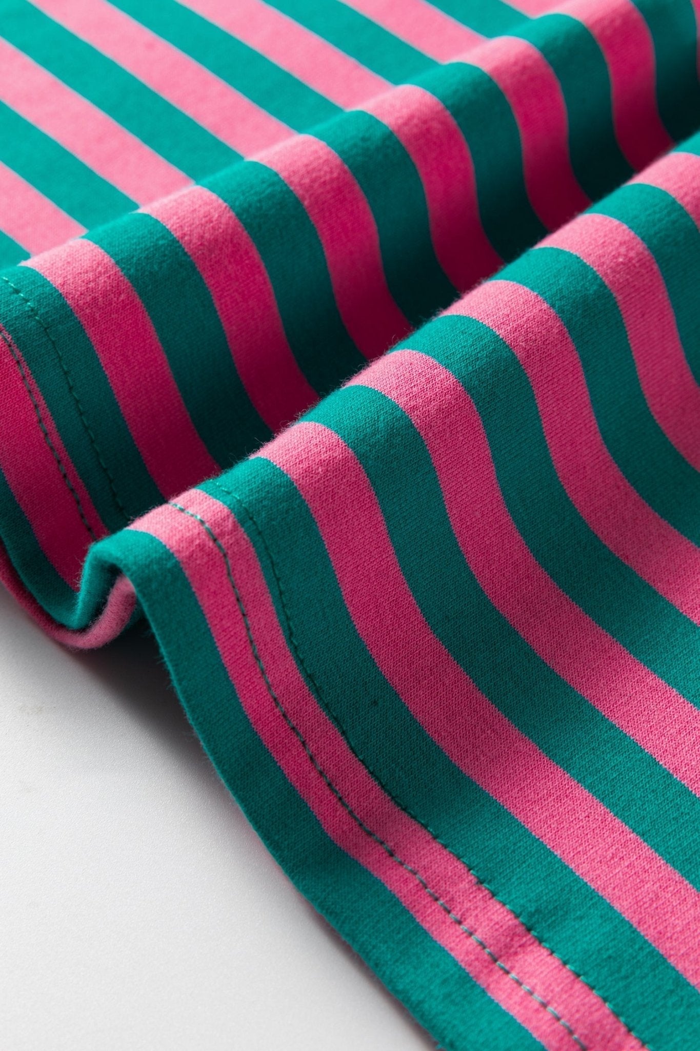 Close-up of pink and green striped fabric on a light gray background