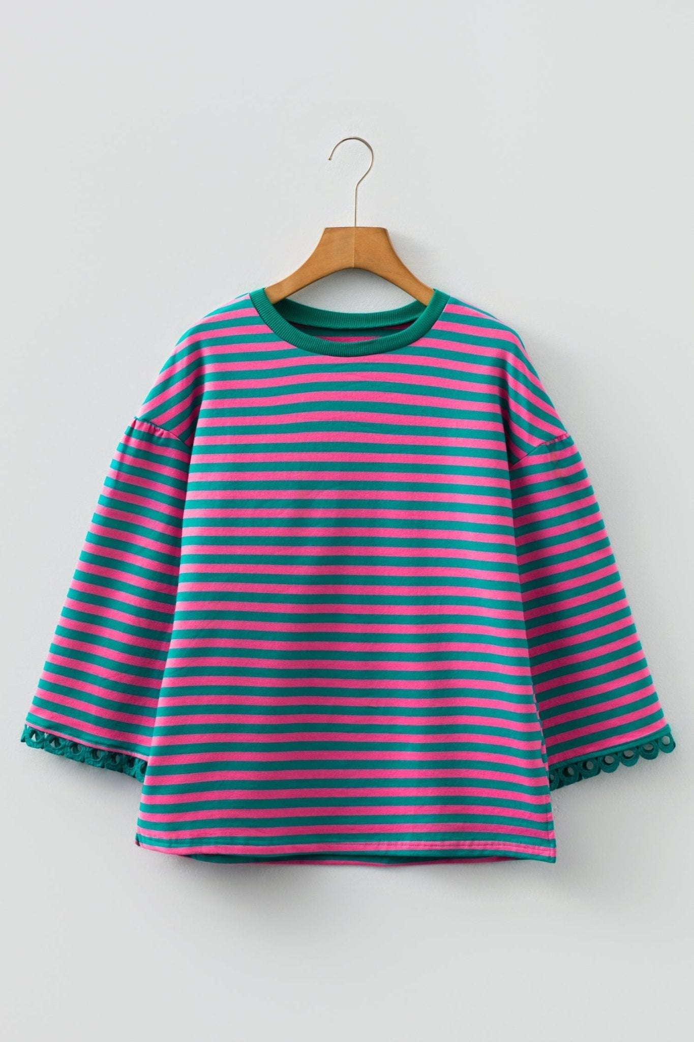 Striped dress with green and pink horizontal stripes on a wooden hanger against a white background