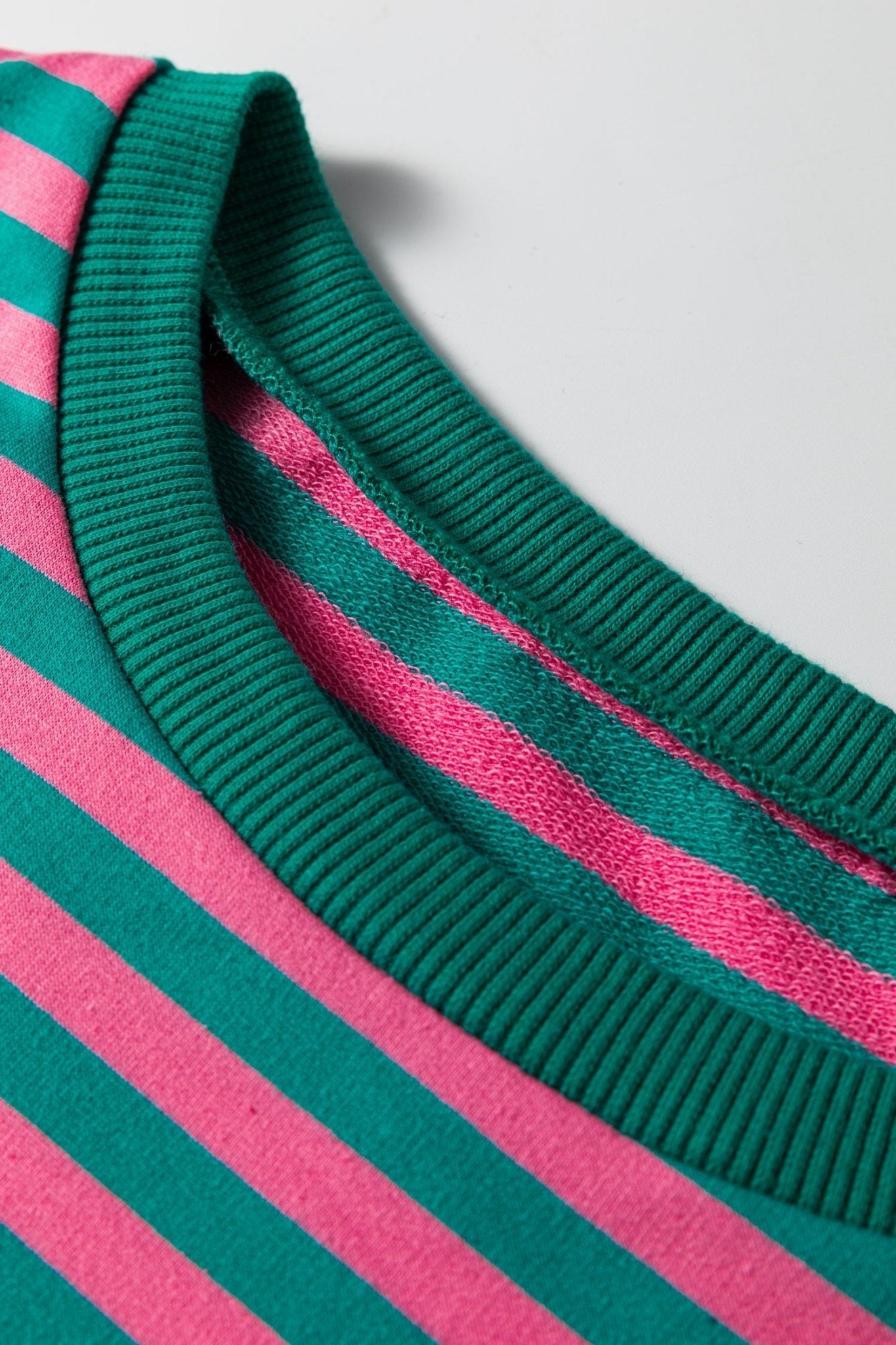 Close-up of a green and pink striped fabric with a plain background