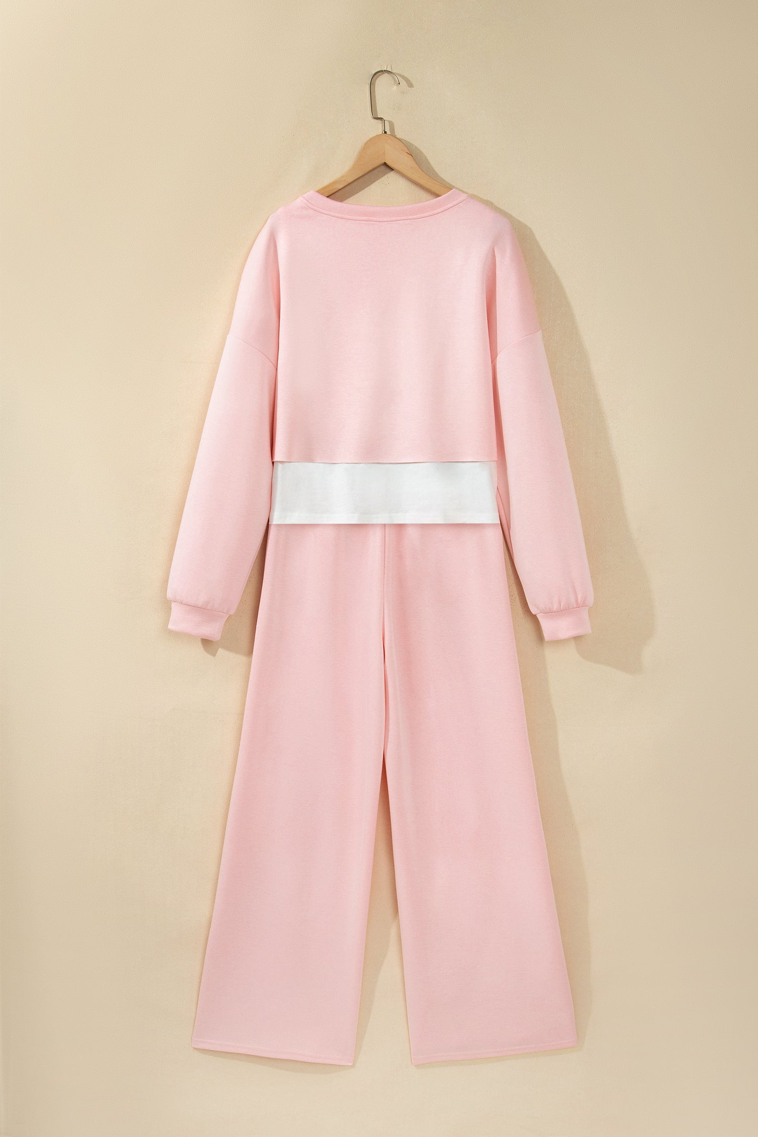 Pink crop top and wide leg pants set on a hanger, back view