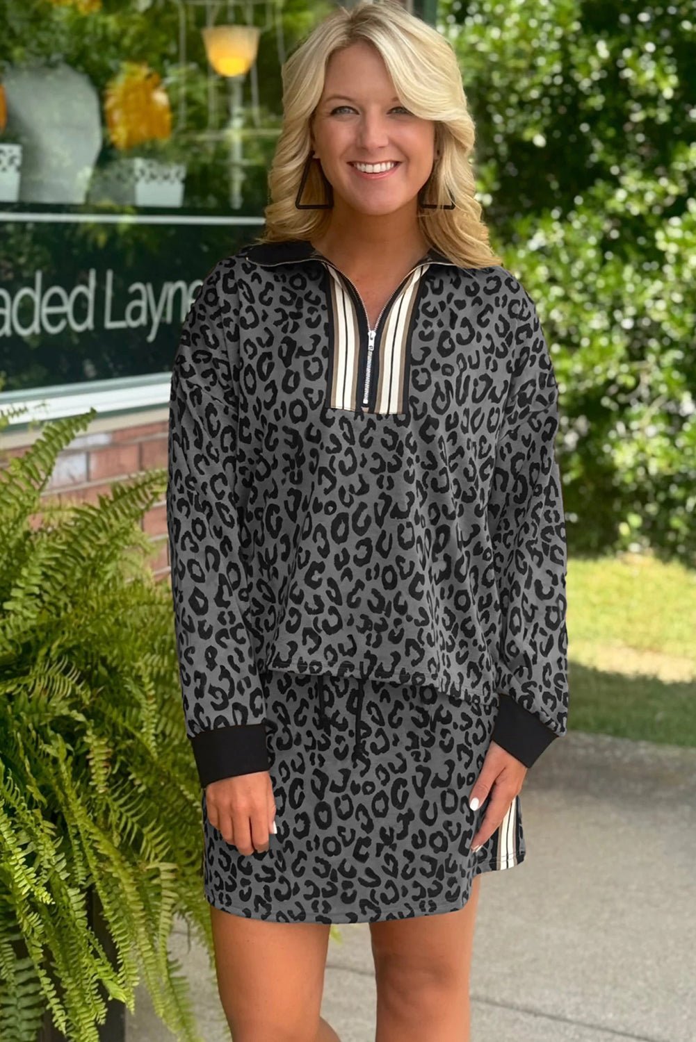 Woman wearing a leopard print dress with a black and white zipper outdoors.