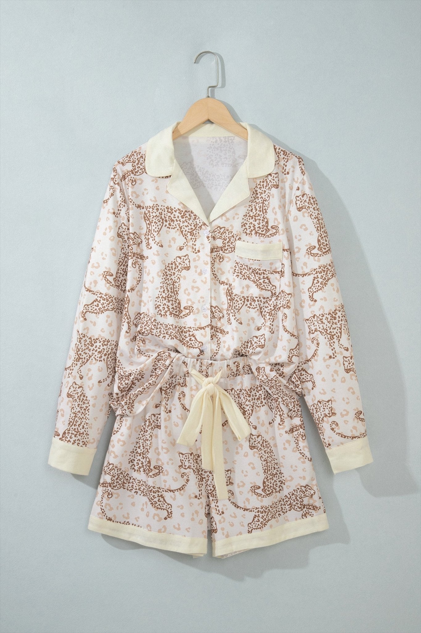 Two-piece pajama set with cream collar and tie belt on wooden hanger.