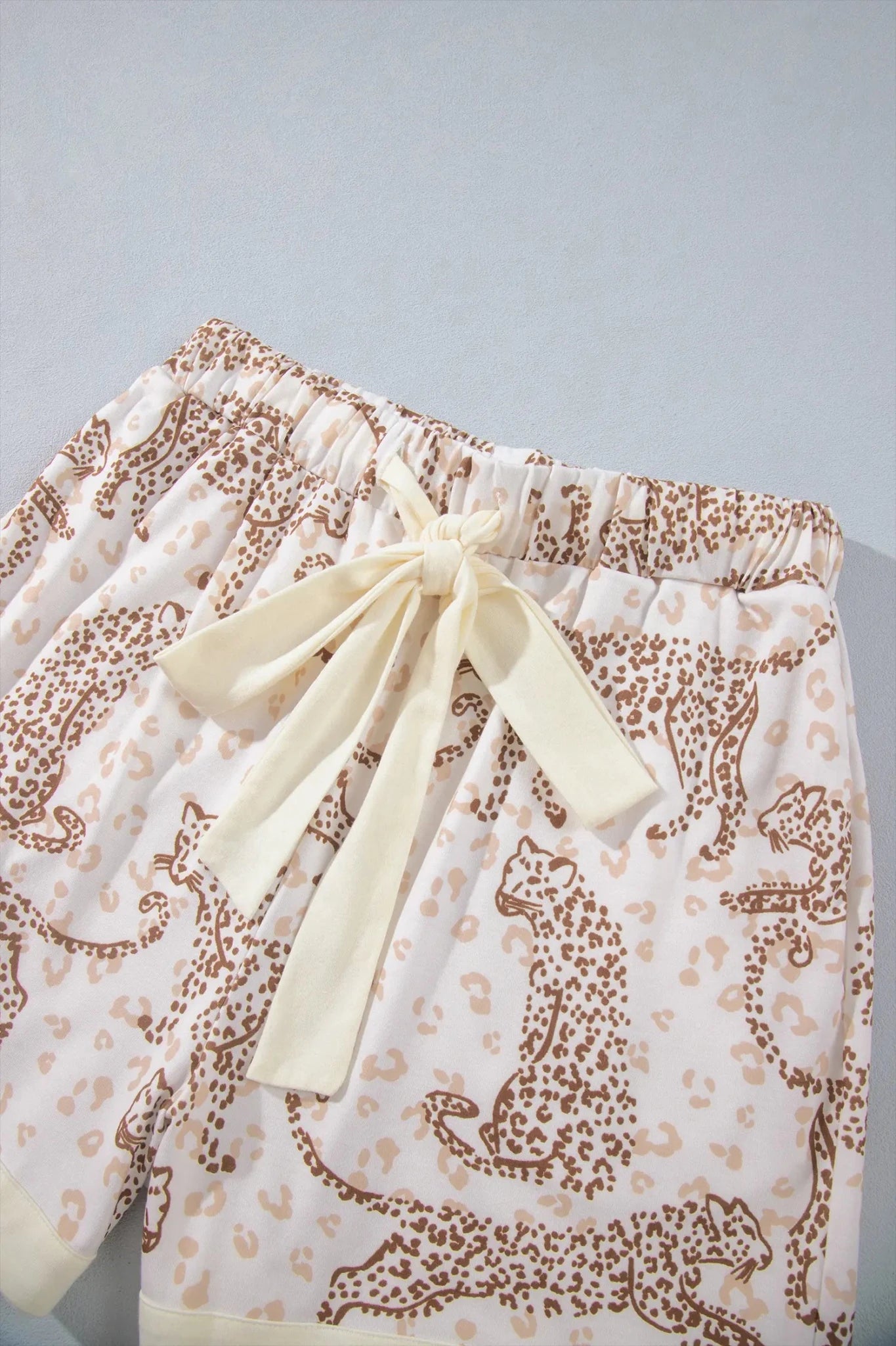 Close-up of cream leopard-print shorts with matching waist tie bow.