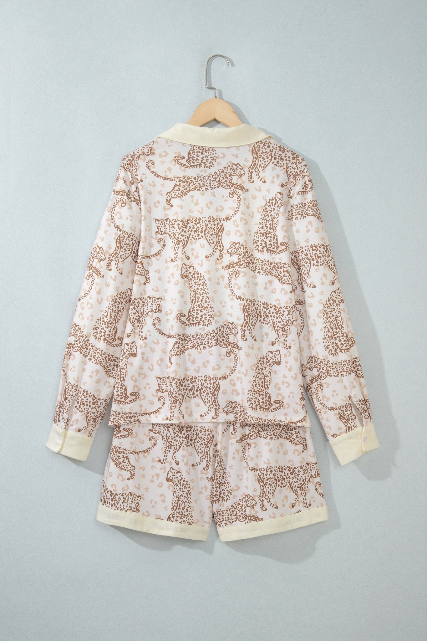Cream leopard-print pajama set with solid cuffs and hem on wooden hanger.