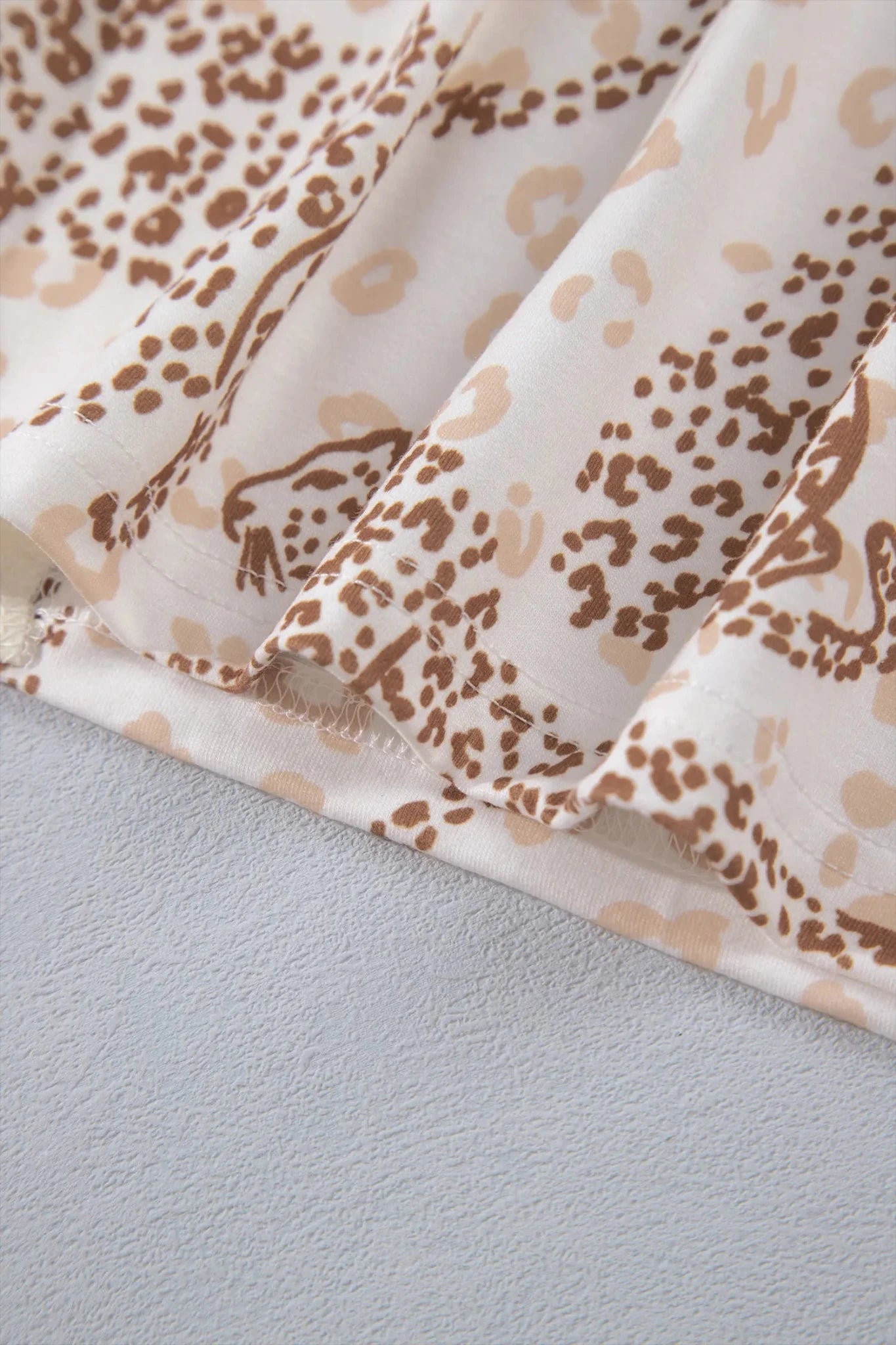 Close-up of pleated white fabric with brown and beige spotted pattern.