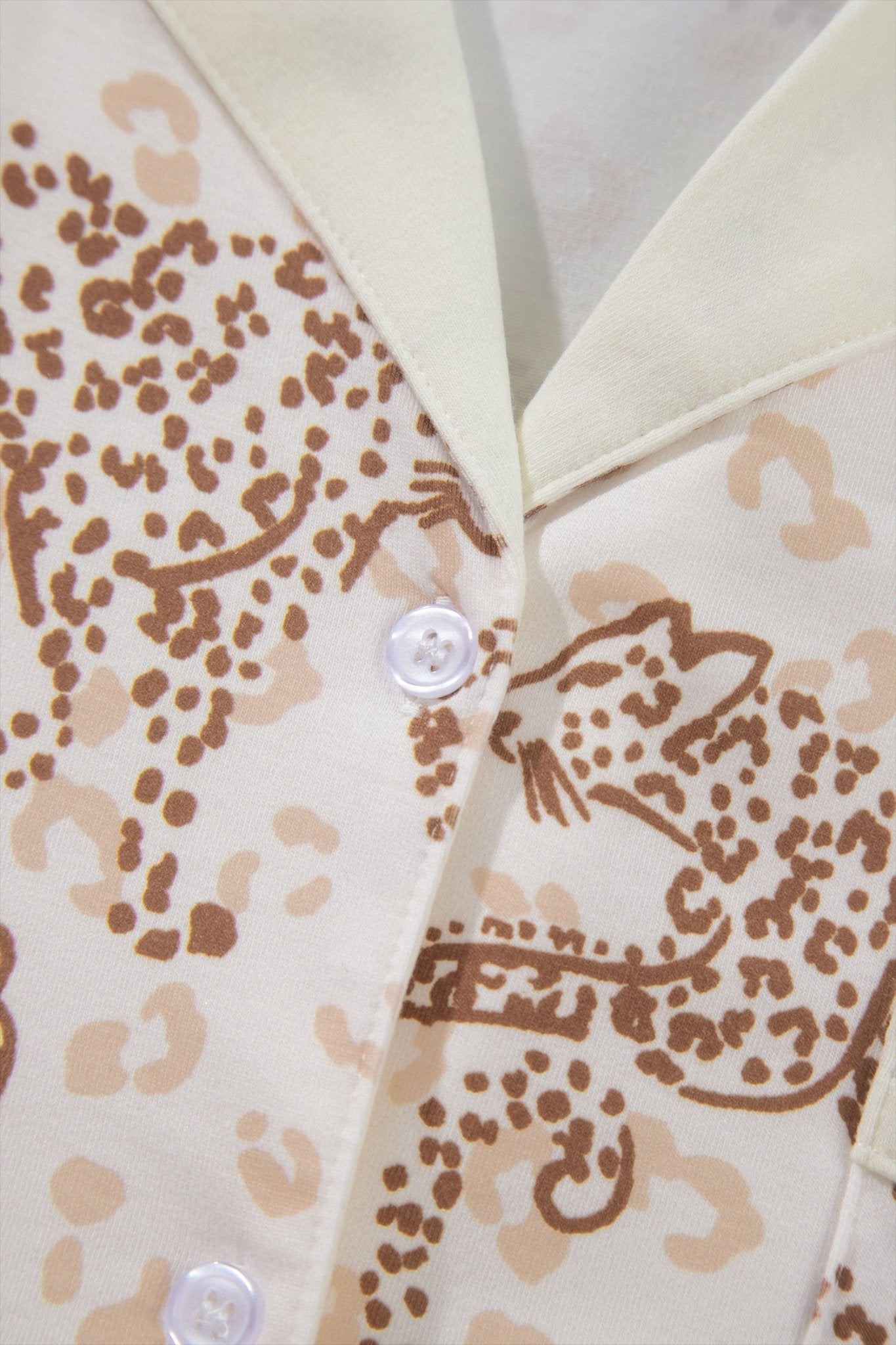 Close-up of cream button-up shirt with brown leopard print and collar.