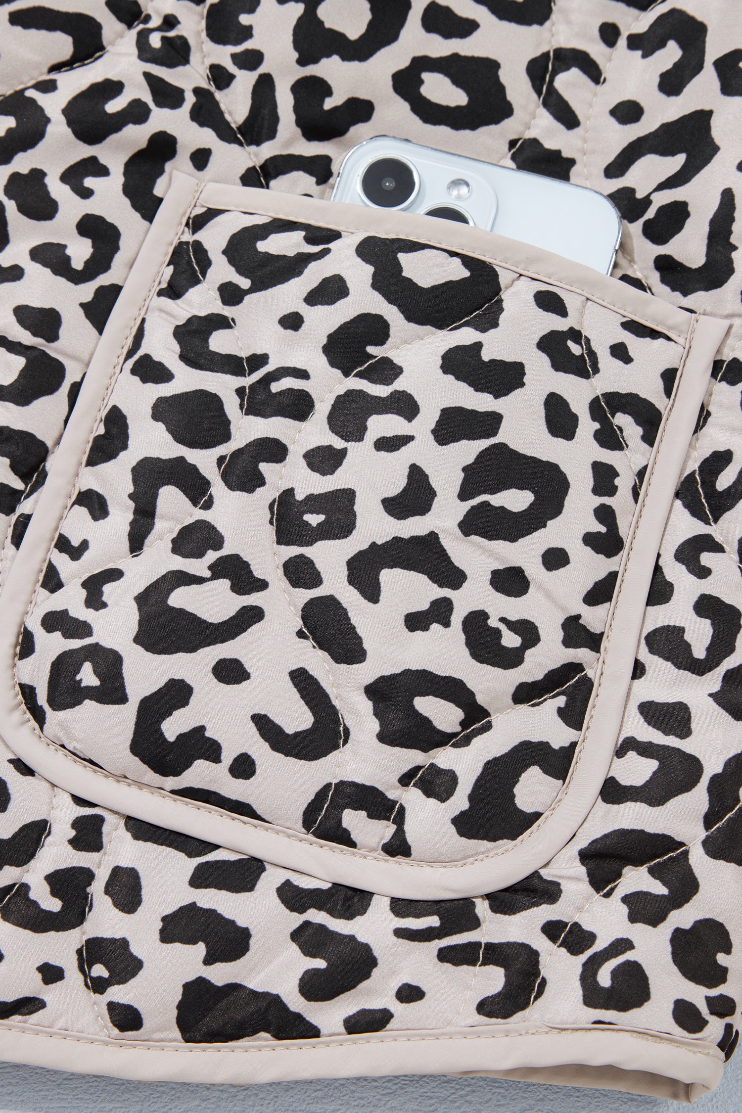 Leopard quilted jacket patch pocket with cream binding holding a phone