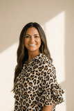 Woman wearing a leopard print blouse against a neutral background