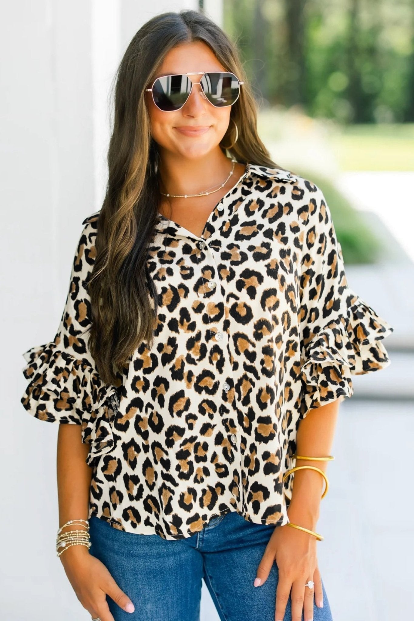Woman wearing a leopard print blouse with ruffled sleeves outdoors.