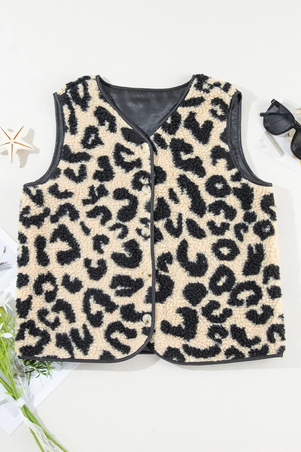 Leopard print vest on a white background with sunglasses and flowers.