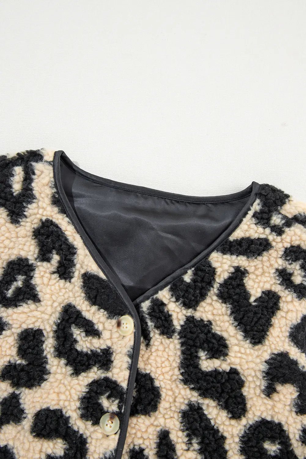 Close-up of a leopard print garment with a black interior lining on a white background