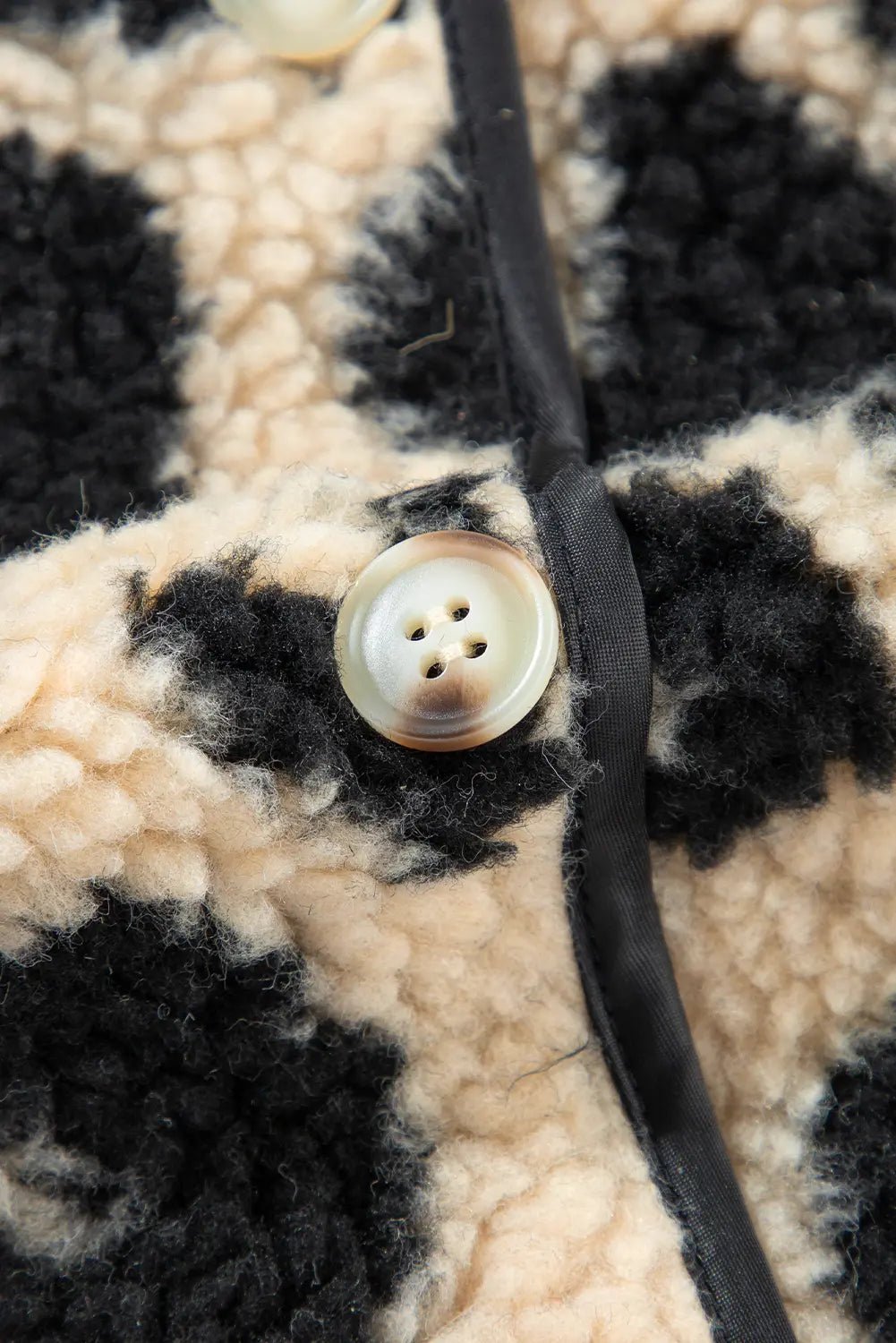 Close-up of a button on a textured fabric surface with a black cord.