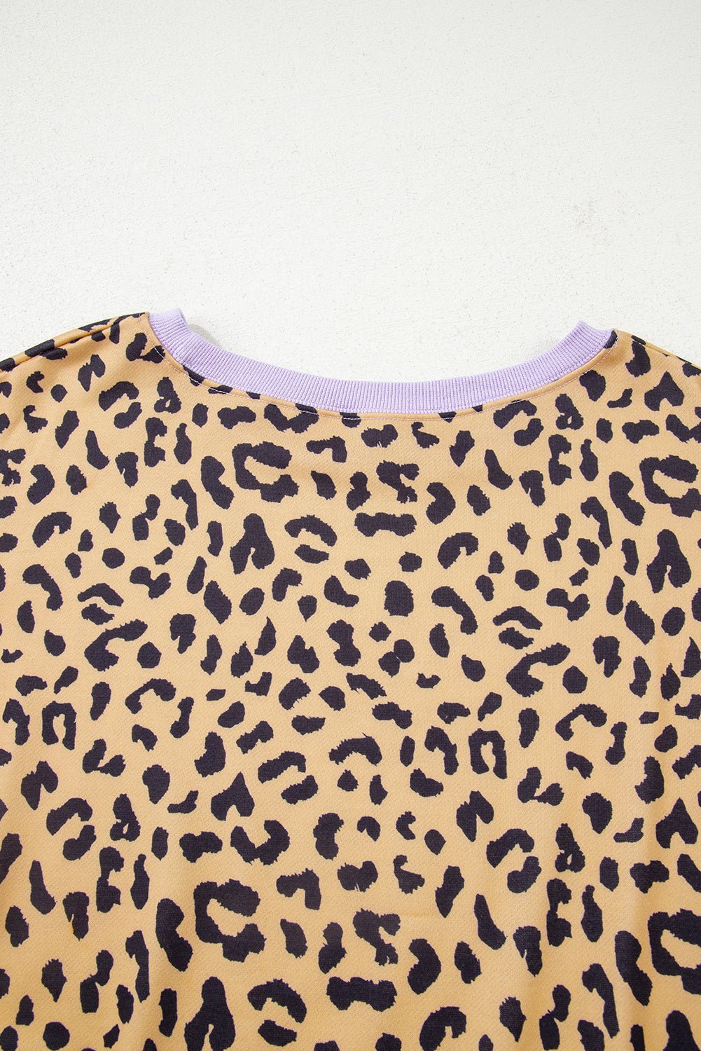 Close-up of a leopard print garment with a light purple trim on a white background