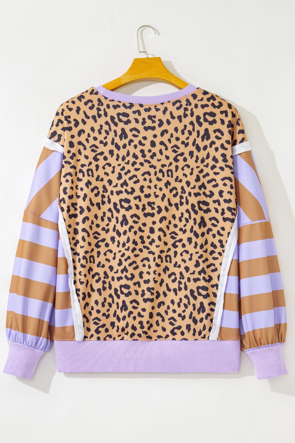 Leopard print sweater with purple accents on a hanger against a white background