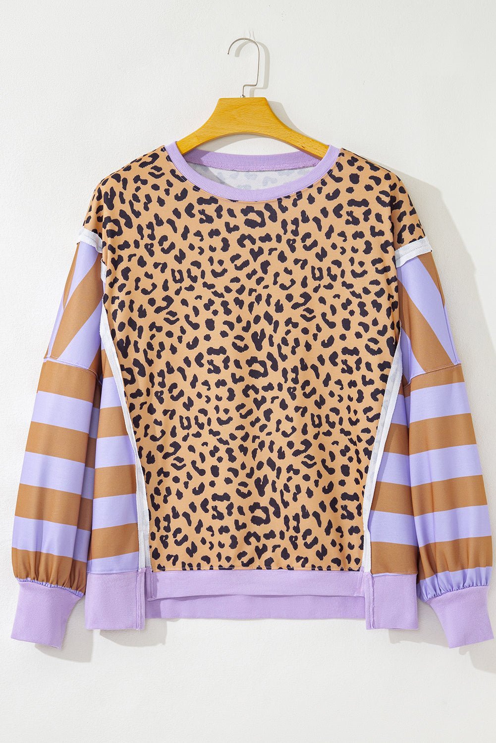 Leopard print sweatshirt with purple and brown sleeves on a hanger against a white background