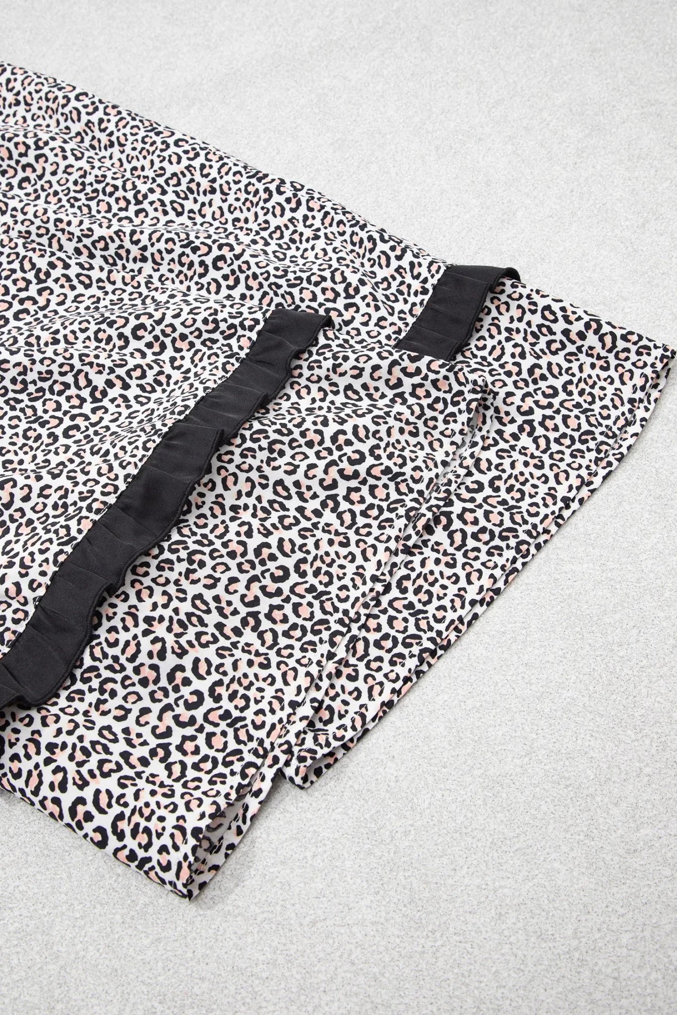 Leopard print fabric with black and beige pattern and ruffled trim.