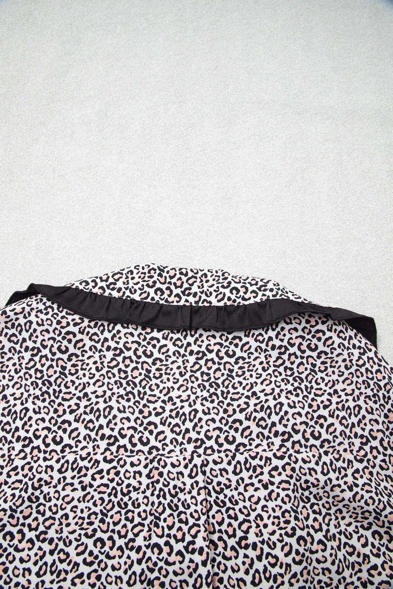 Leopard print garment with black ruffled waistband on a white base.