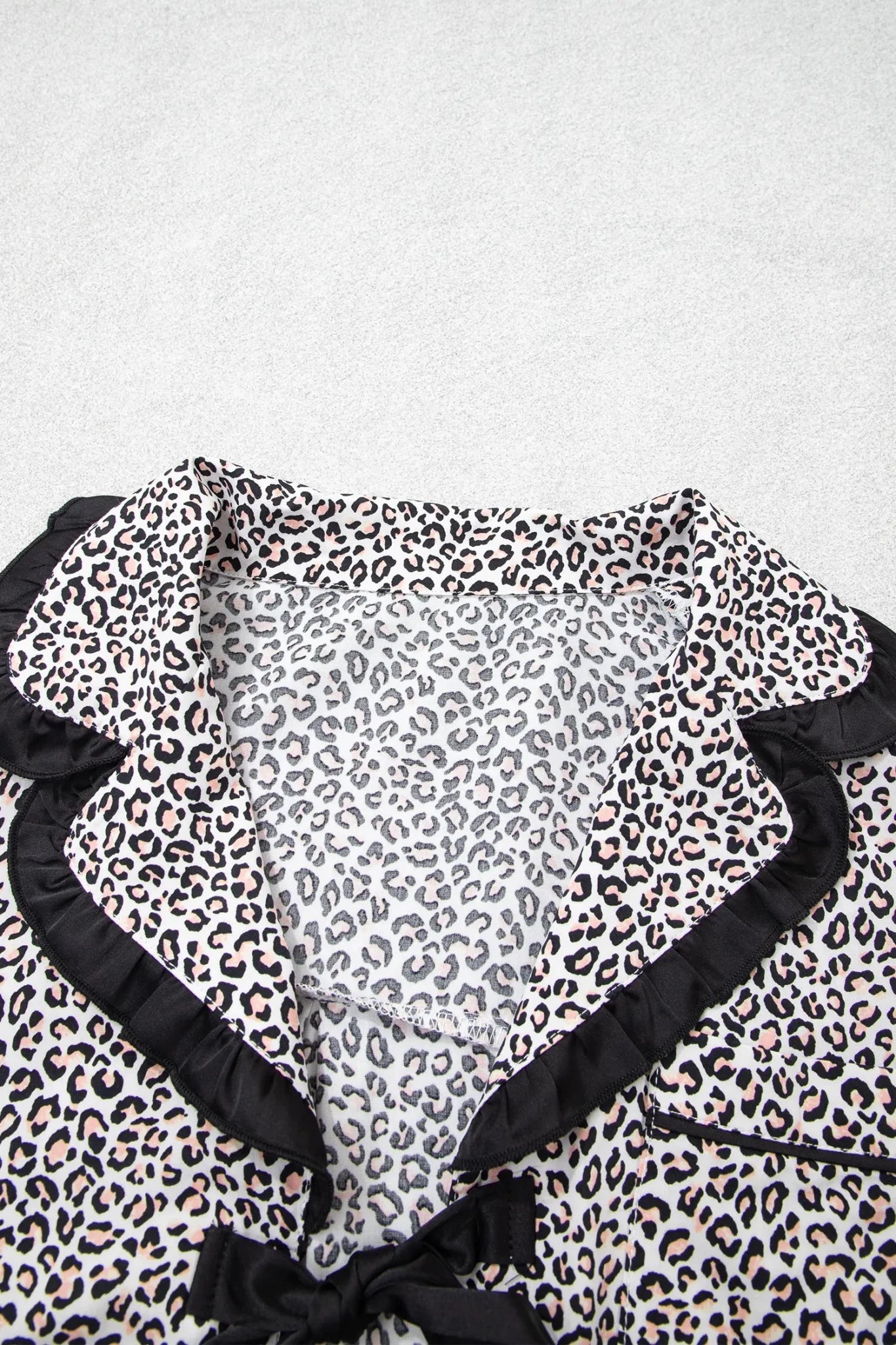 Leopard print blouse with black ruffled trim and bow neckline.