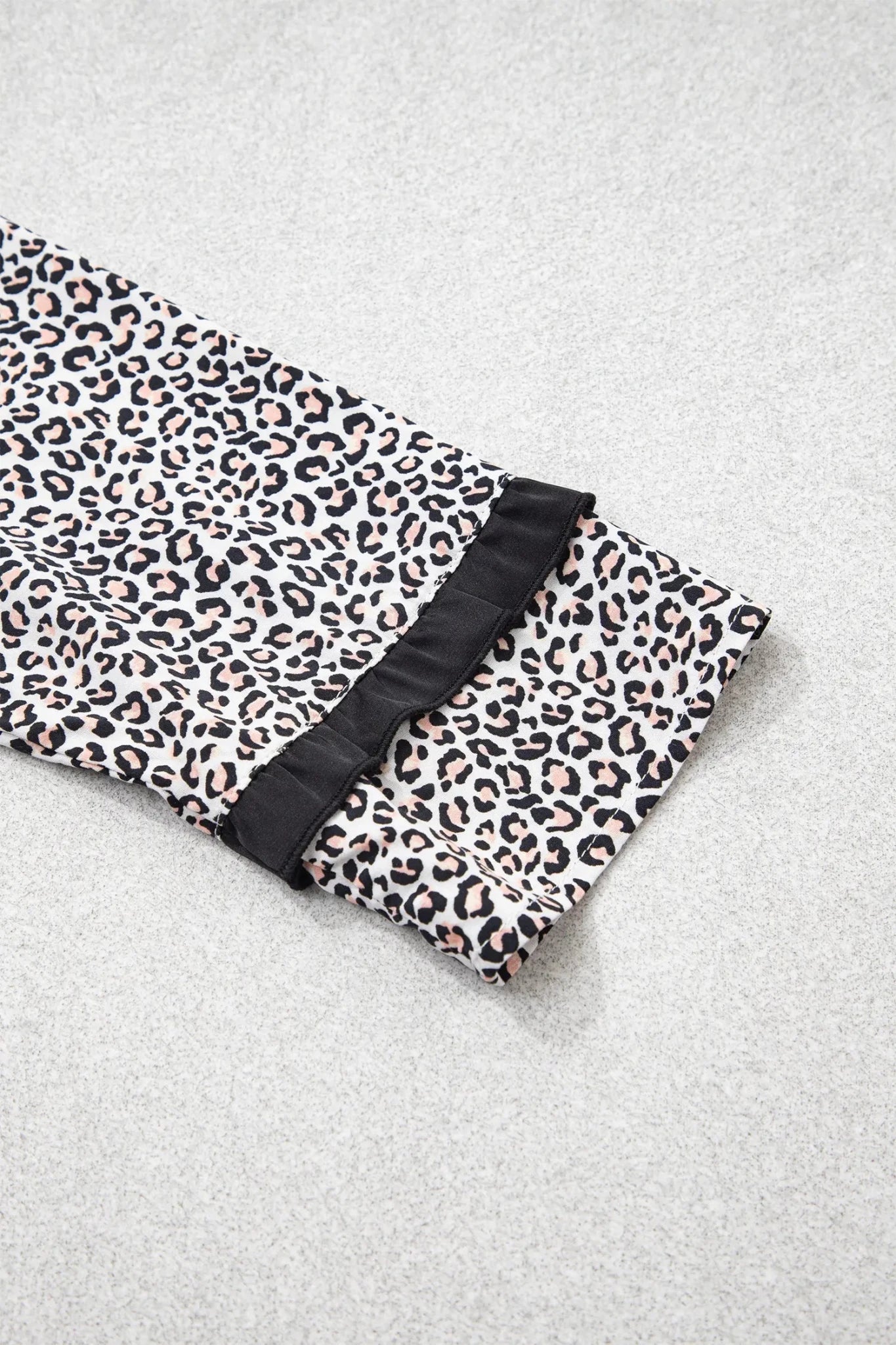 Leopard print sleeve with black ruffled trim on gray fabric.