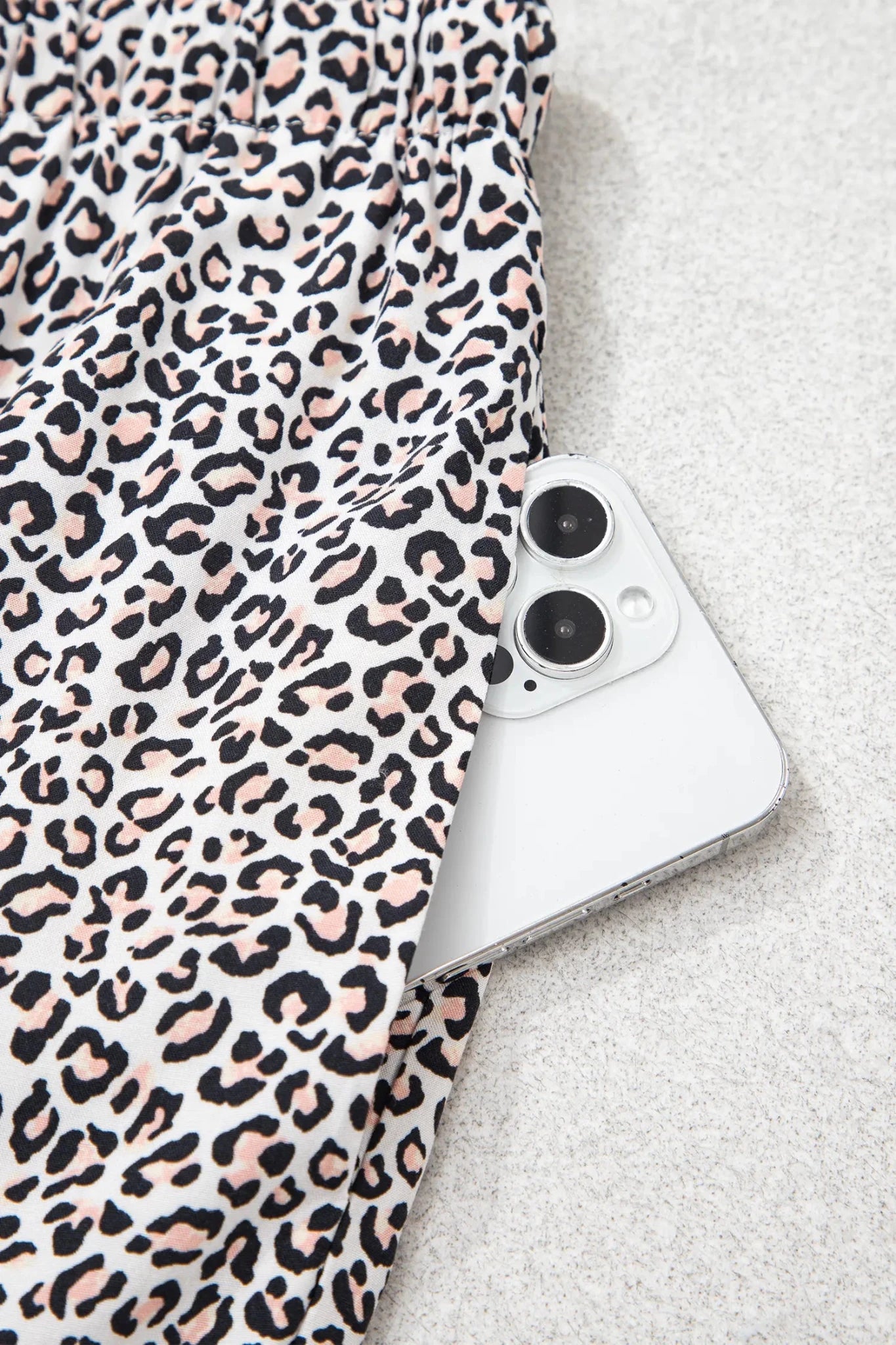 Leopard-print fabric with a white smartphone on gray surface.