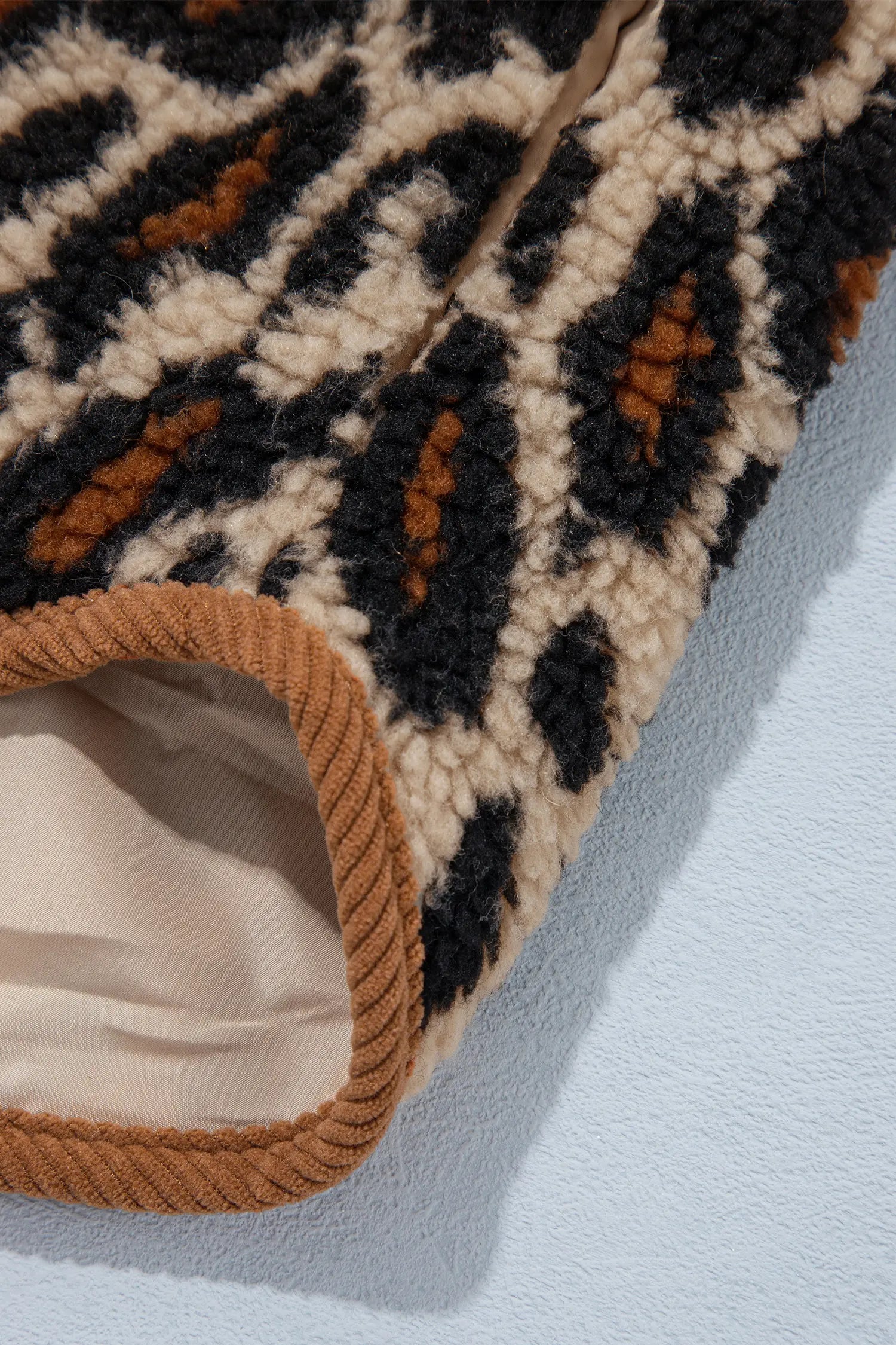 Close-up of leopard sherpa fabric, corduroy trim and cream lining