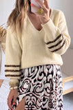 Woman wearing a cream knit sweater with leopard sleeves and a patterned skirt.