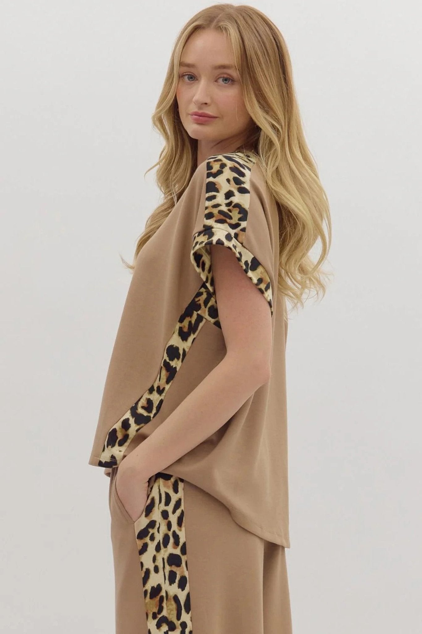 Woman wearing a beige outfit with leopard print accents on a white background