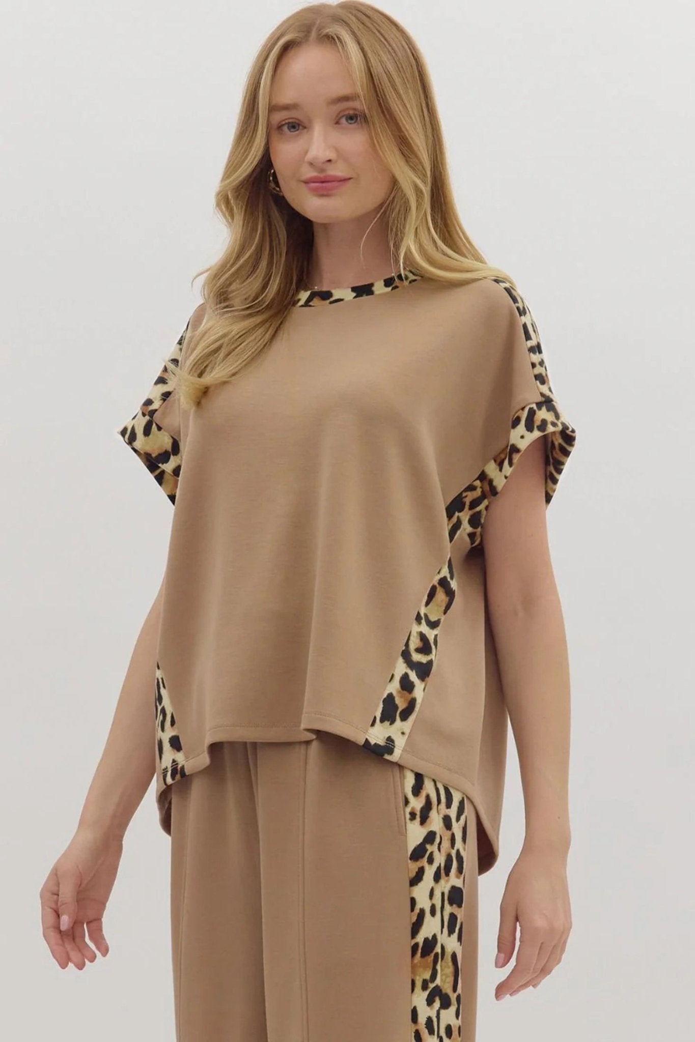 Woman wearing a beige outfit with leopard print sleeves and hem on a white background