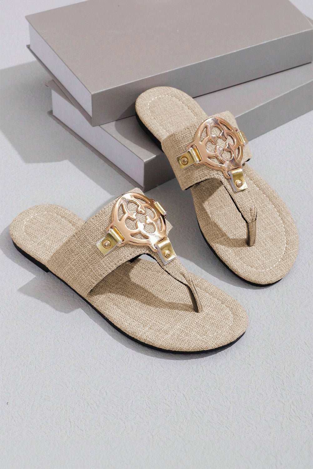Beige sandals with gold accents on a light gray surface