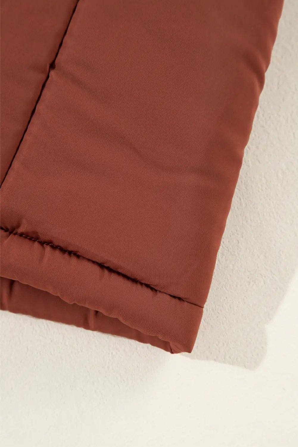 Close-up of a brown quilted blanket on a white surface