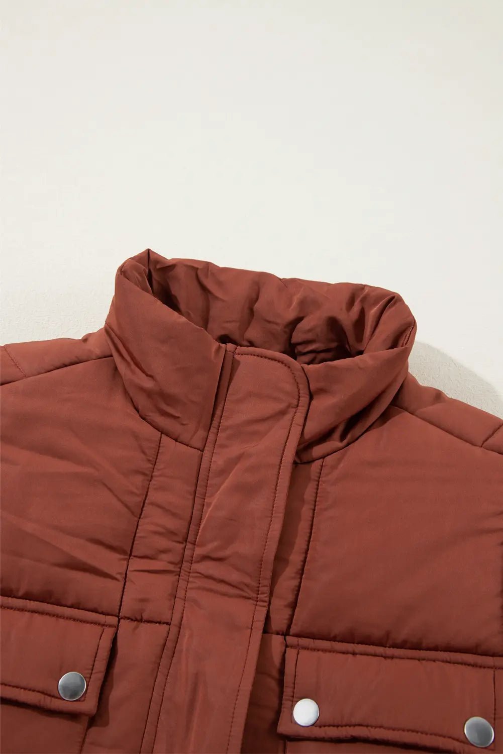Brown puffer jacket with silver buttons on a white background