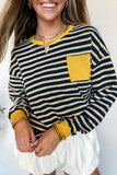 Woman wearing a navy and yellow striped long-sleeve shirt with a pocket on a light background