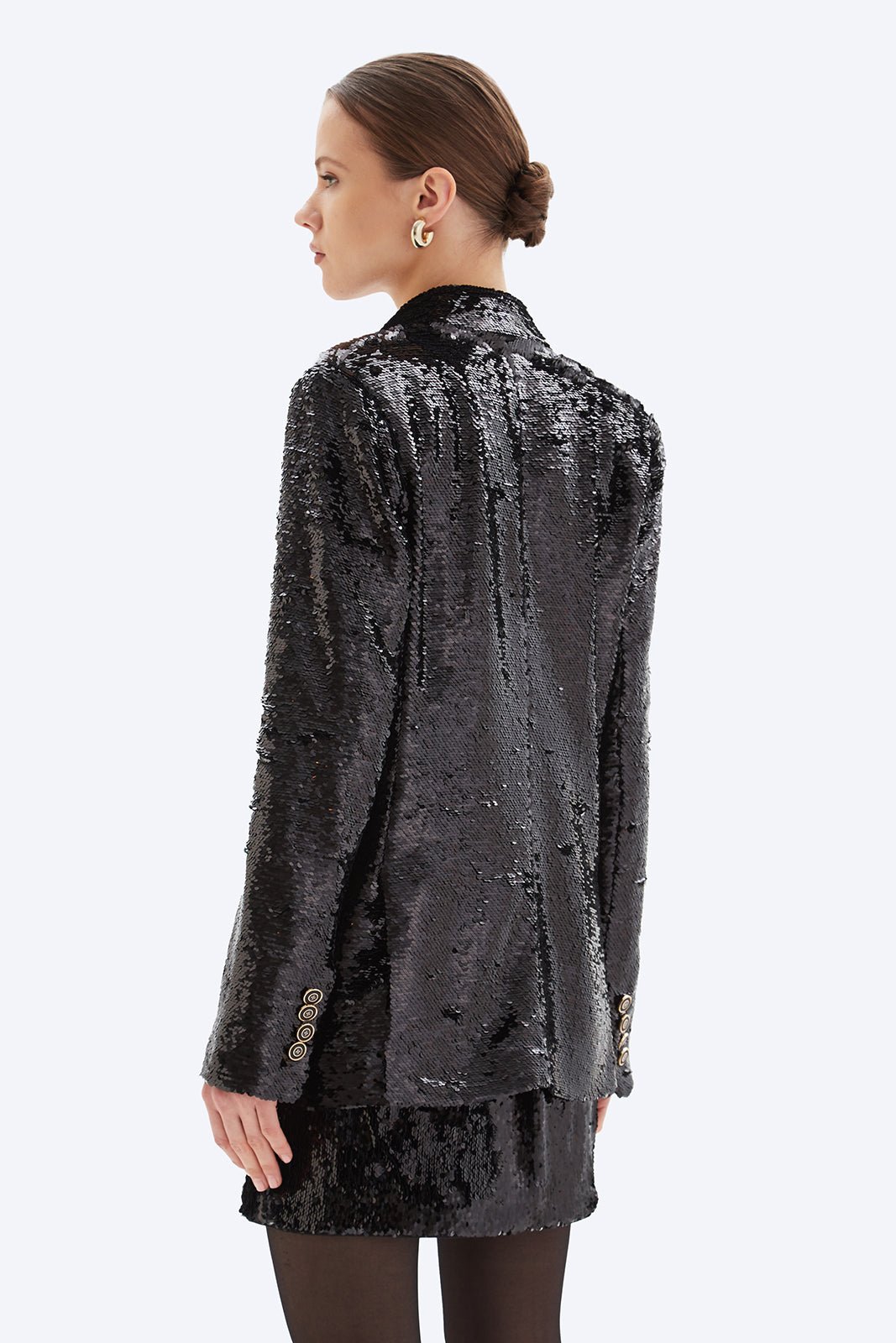 Woman wearing a black sequin jacket on a white background