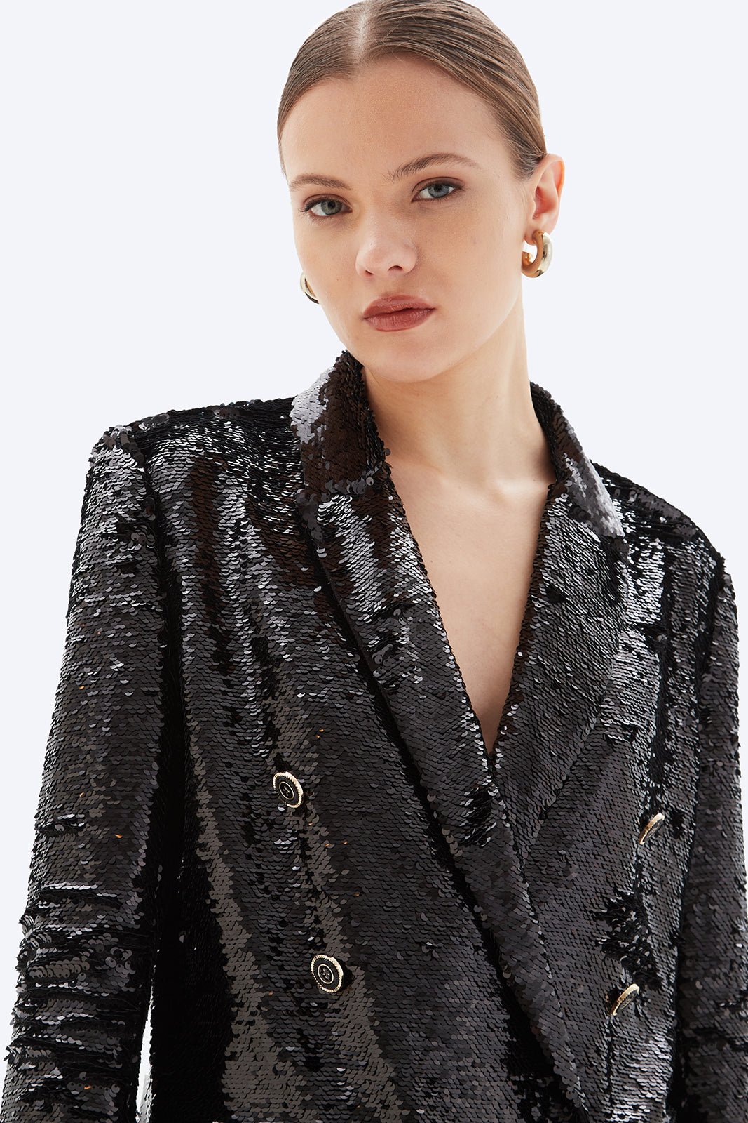 Woman wearing a black sequin blazer on a white background