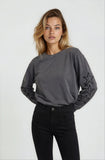 Woman wearing a gray long-sleeve top with star designs on a white background
