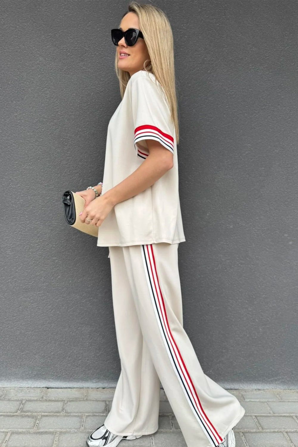 Woman wearing a white outfit with red stripes against a gray background
