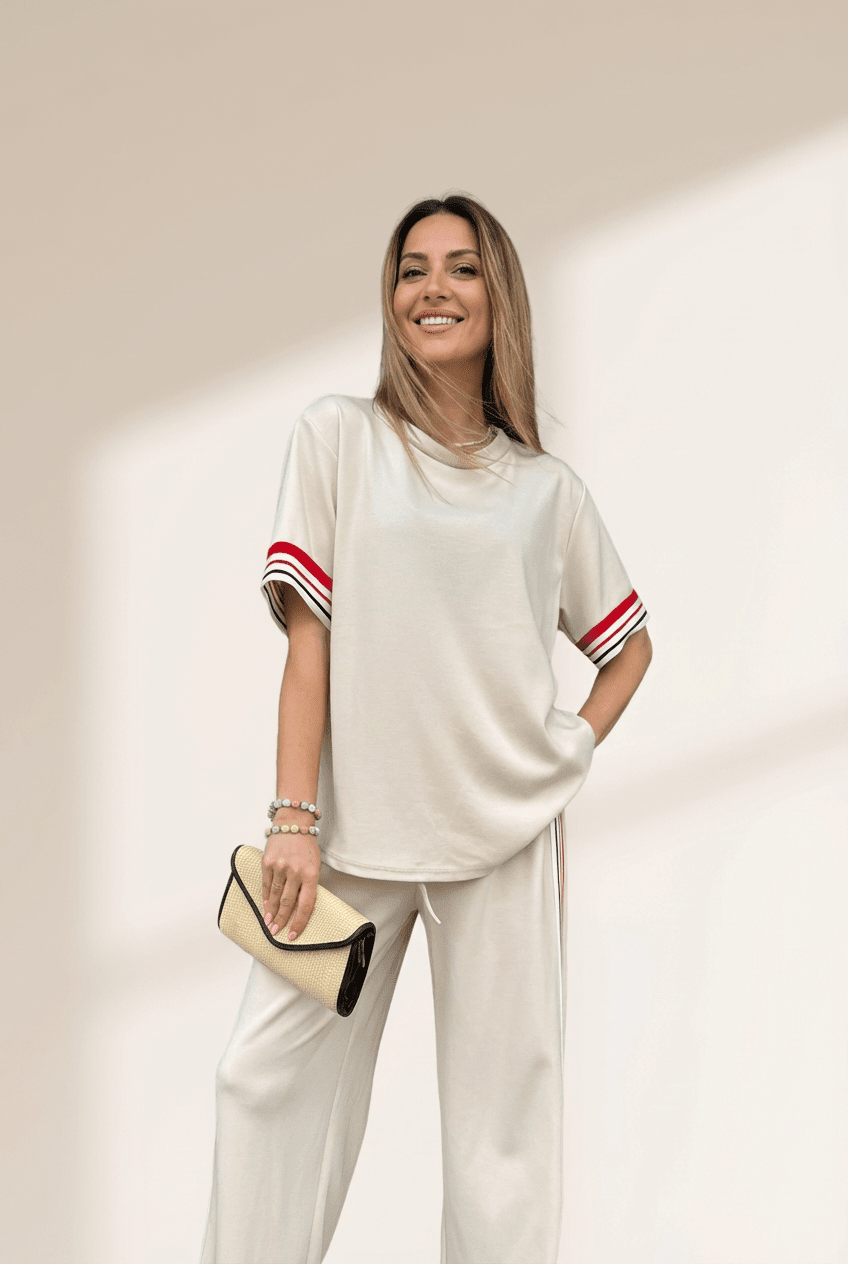 Woman wearing a white outfit with red accents against a beige background