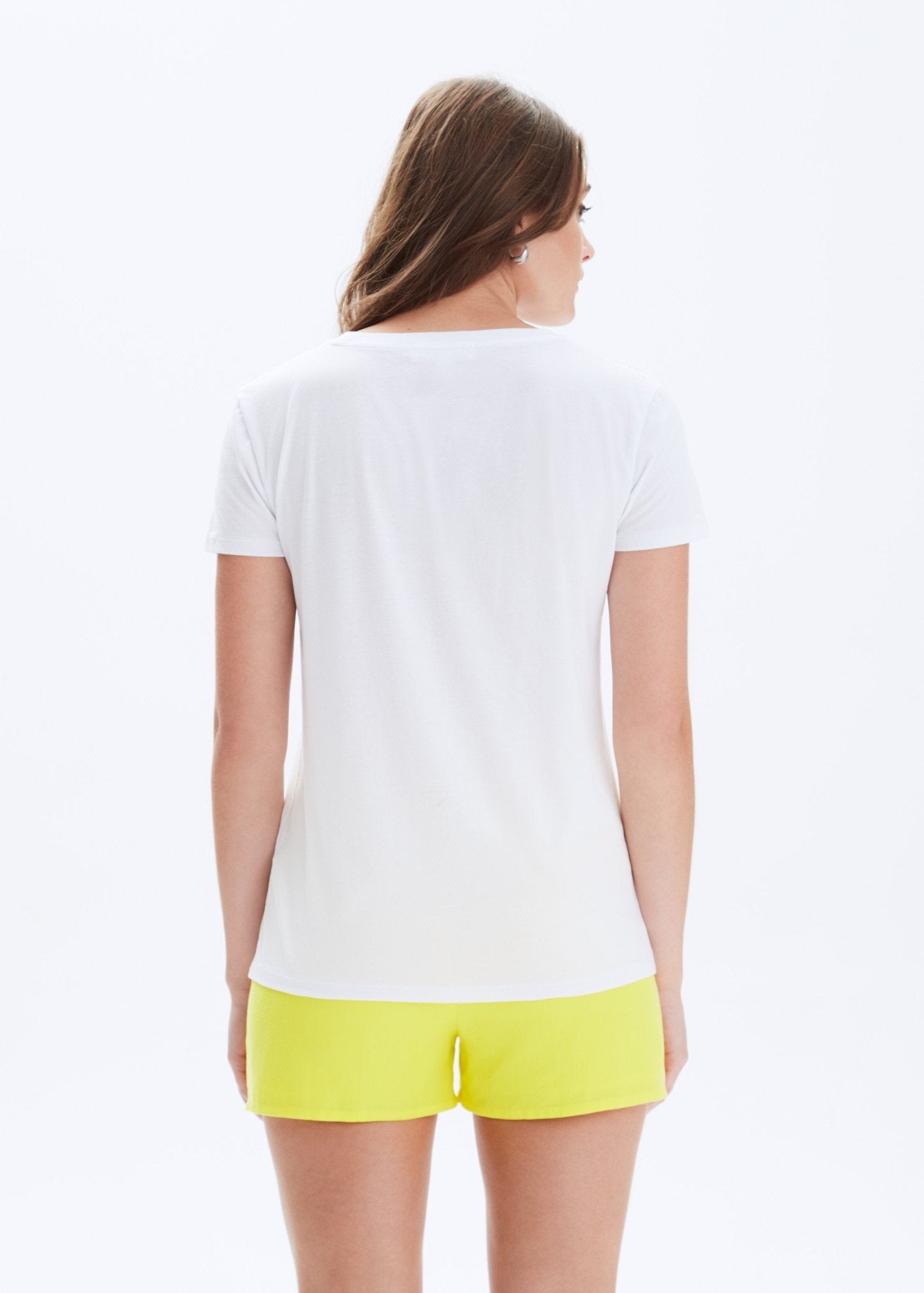 Woman wearing a white t-shirt and yellow shorts on a white background