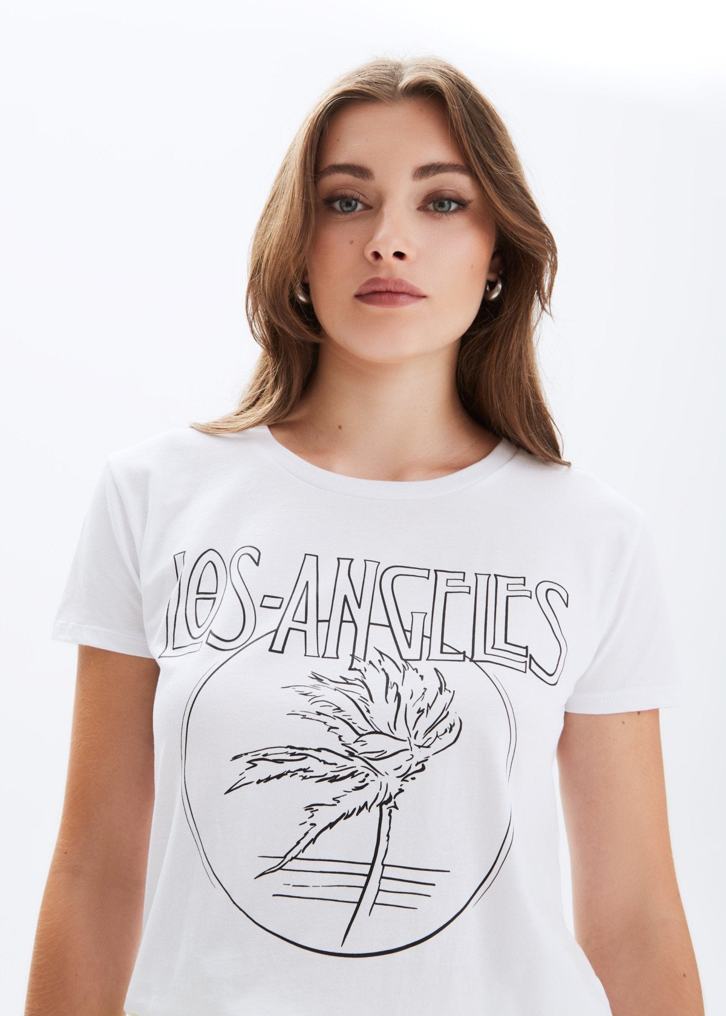 Woman wearing a white t-shirt with 'Los Angeles' and palm tree design.