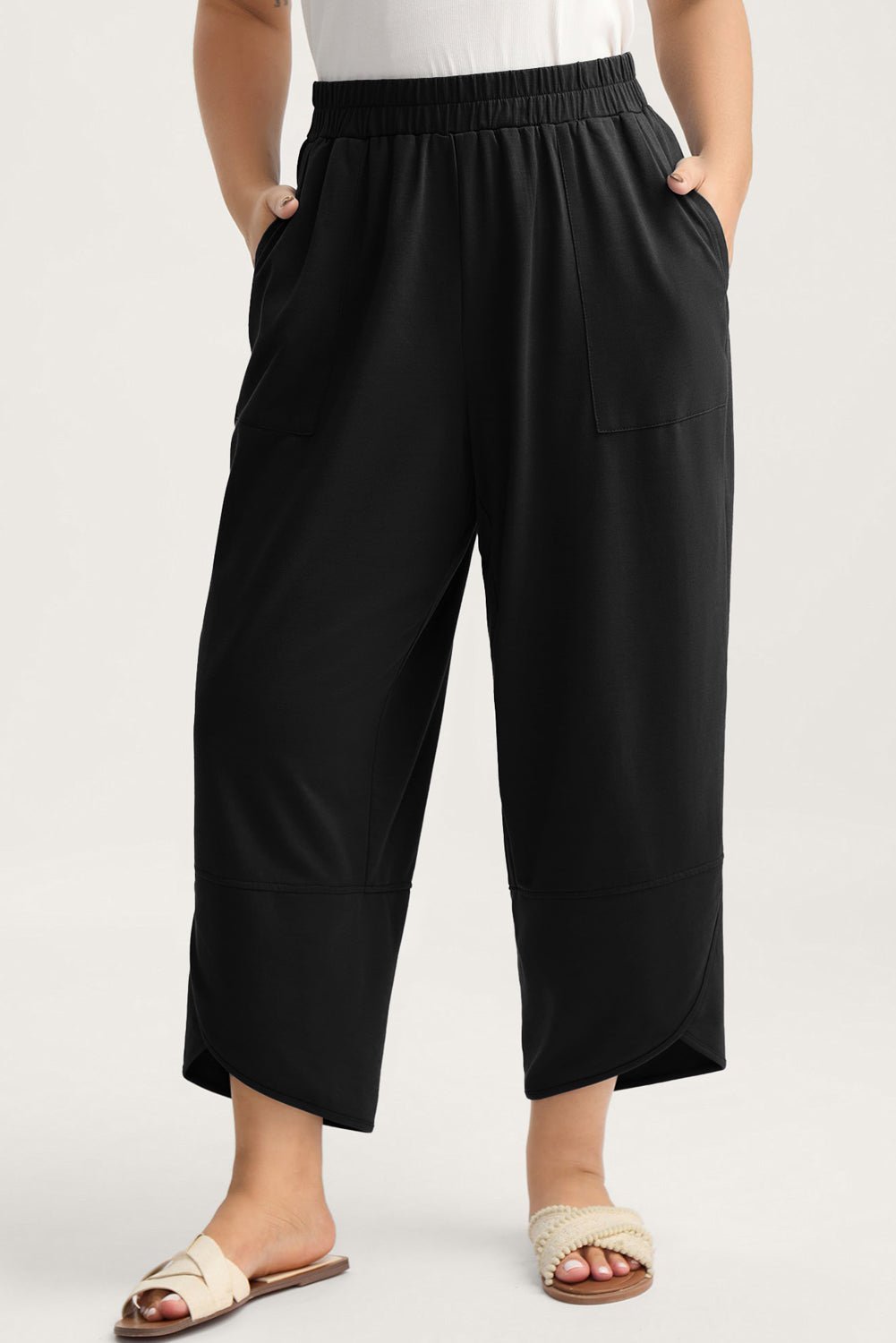 Person wearing black wide-leg pants on a white background