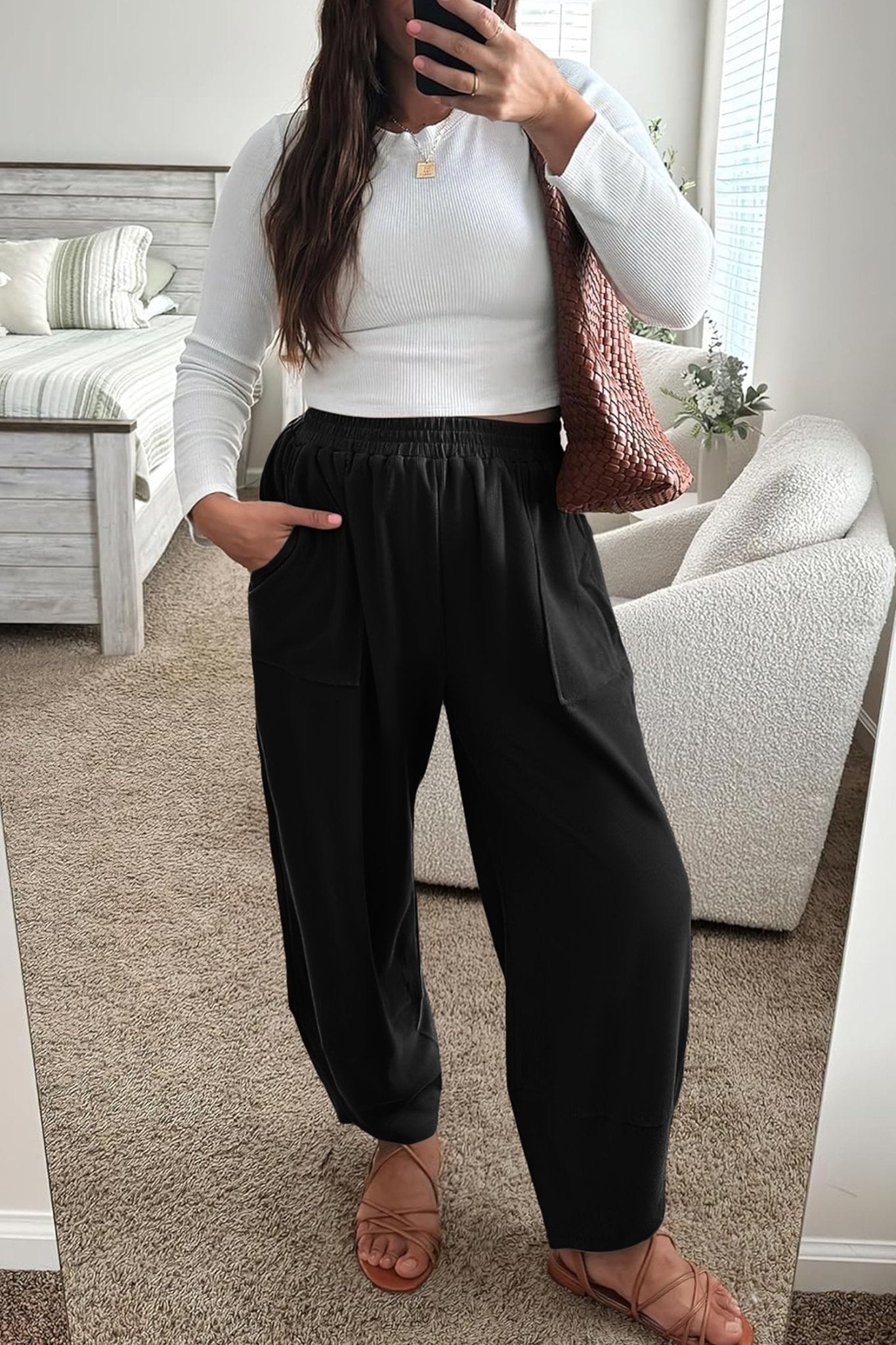 Person wearing a white top and black pants in a living room.