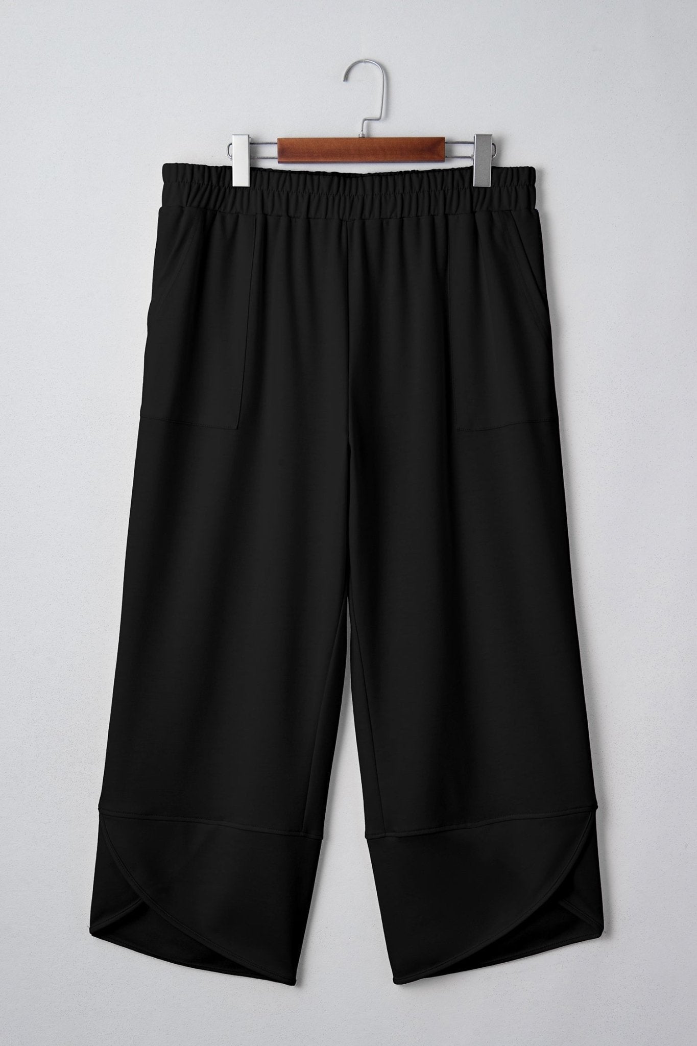 Black wide-leg pants on a hanger against a white background