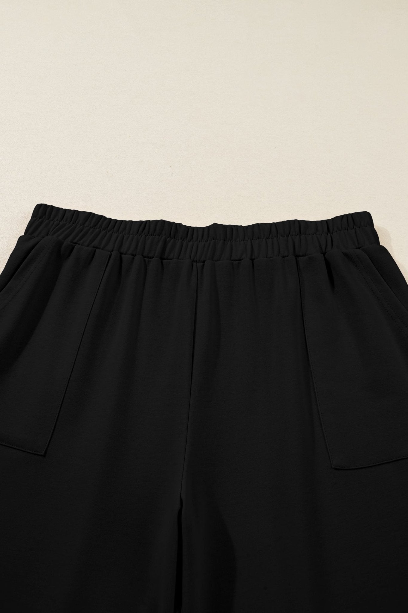 Black pants with an elastic waistband on a beige background