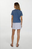 Woman wearing a blue t-shirt and light-colored skirt on a white background