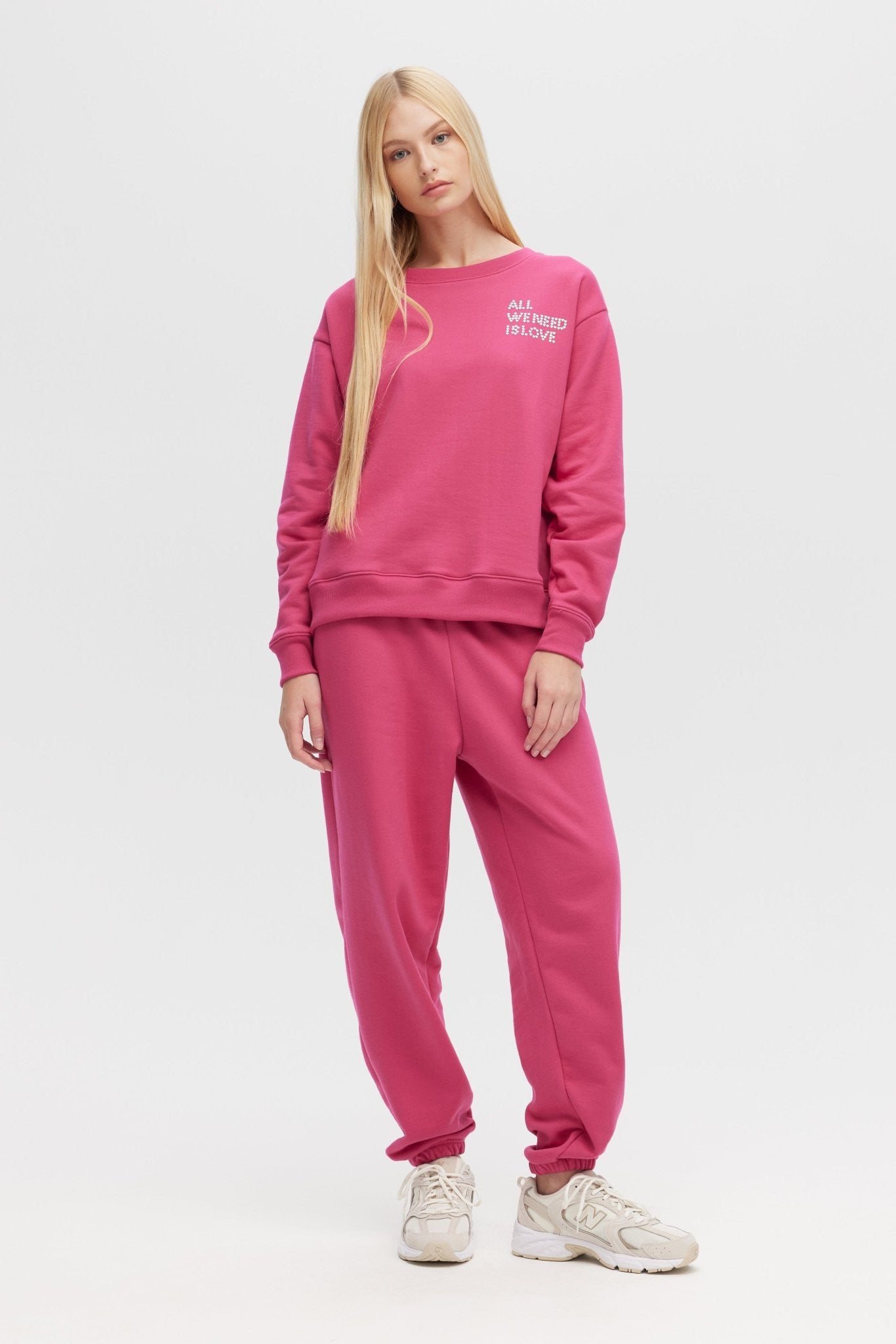 Woman wearing a pink tracksuit with text on a white background