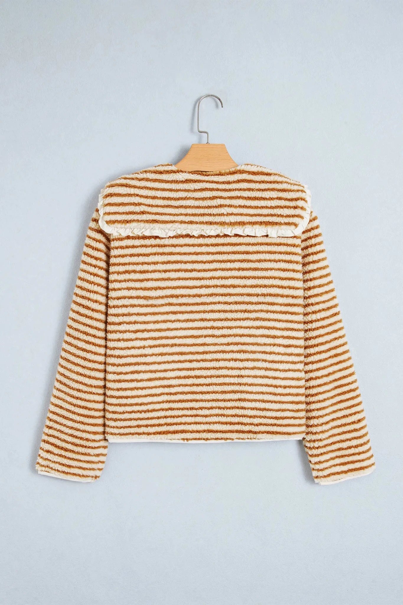 Mustard brown and cream striped cropped fuzzy knit sweater on hanger.