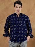 Man wearing a dark blue patterned shirt against a brown background