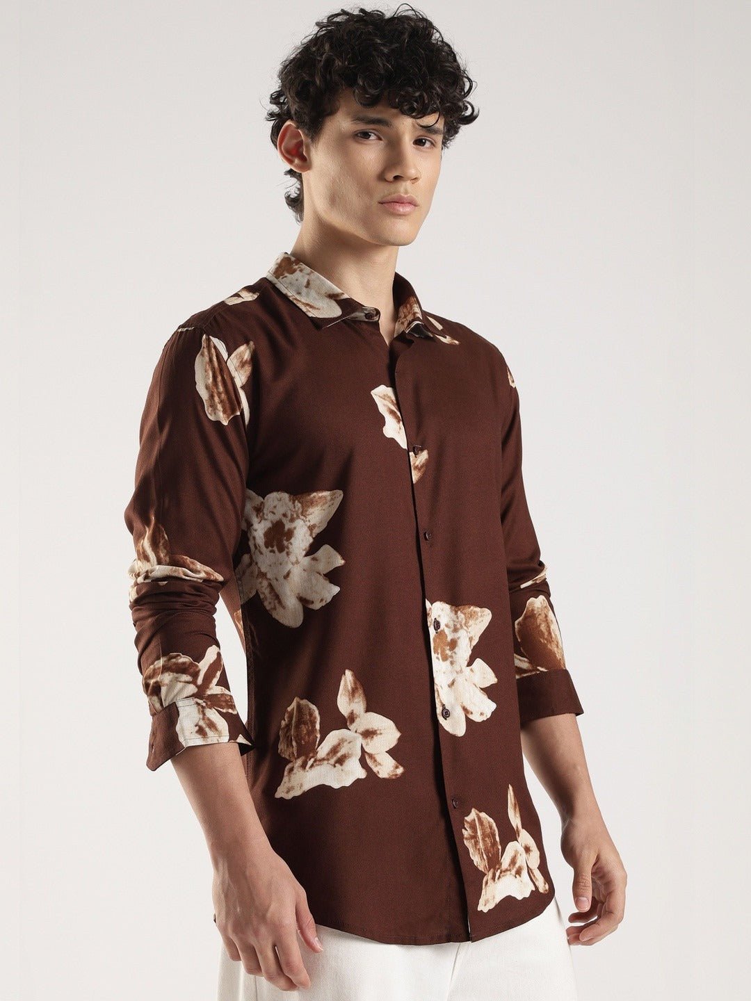Man wearing a brown floral patterned shirt on a white background